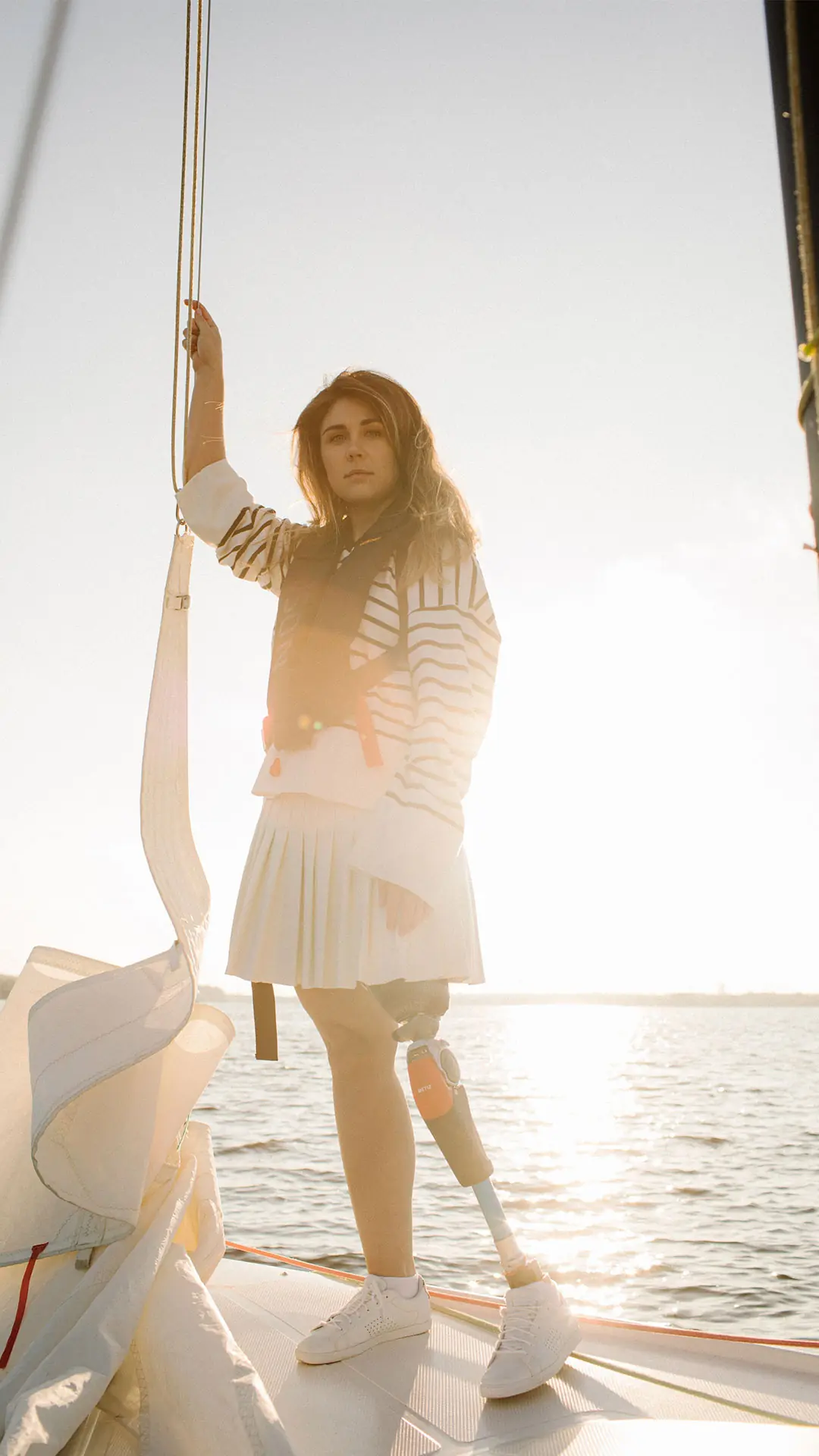 Mulher de pé num veleiro, com prótese de perna e joelho Metiz 6H30